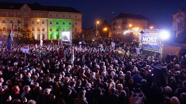 Un rassemblement de nuit avec une foule nombreuse et un bâtiment en éclairage vert.