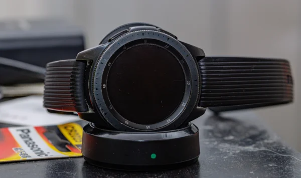 Une SAMSUNG Galaxy Watch noire sur son dock de chargement, le voyant indiquant une charge en cours.