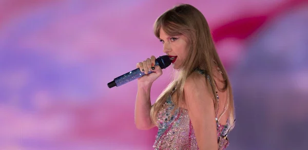 Taylor Swift en plein concert, chantant dans un micro bleu scintillant.