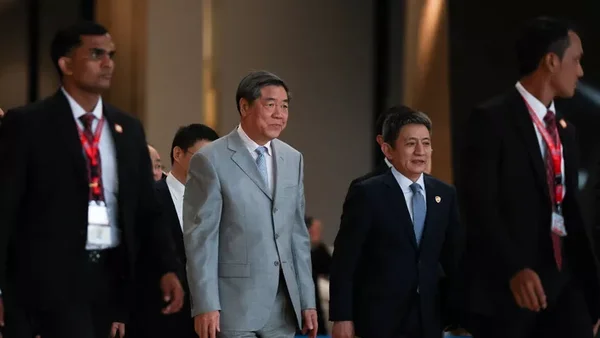 Deux hommes en costume et cravate marchant dans un passage lors de discussions.