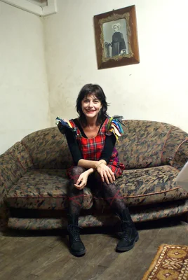 L'icône pop belge Lio posant sur un canapé dans une robe à carreaux rouges.