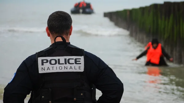 Un gendarme français dans l'eau face à une embarcation gonflable de migrants.