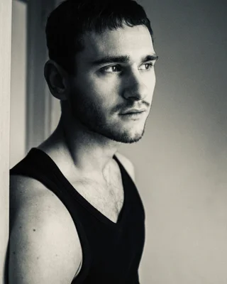 Ulysse Josselin posant en noir et blanc, torse nu sous un débardeur noir.