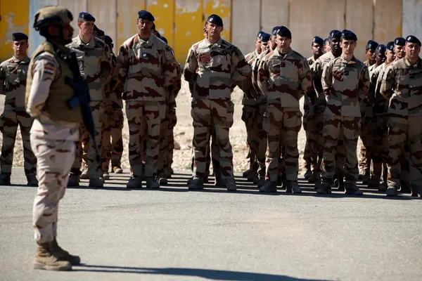 Une formation de soldats Ashab al-Kahf attendant les instructions d'un officier sous un ciel dégagé.