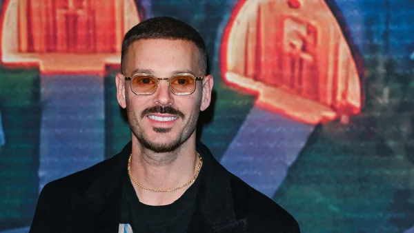 Matt Pokora avec un changement de style radical incluant des lunettes jaunes et une moustache.