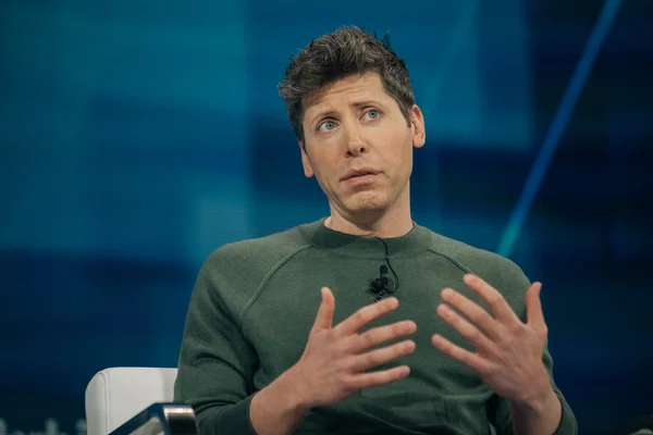 Sam Altman discutant assis sur une chaise blanche.