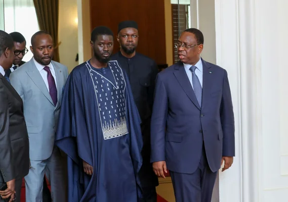 Macky Sall entouré de collaborateurs et de dignitaires en tenues formelles et traditionnelles.