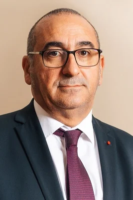 Portrait de Laurent Nuñez, en costume et cravate violette, sur fond neutre.