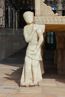 Statue de pierre d'une figure en tenue traditionnelle à côté du Trône de marbre dans le palais du Golestan.