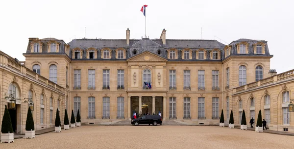 Vue du palais de l'Élysée à Paris, avec son entrée colonnée, sa cour intérieure et le drapeau français flottant.