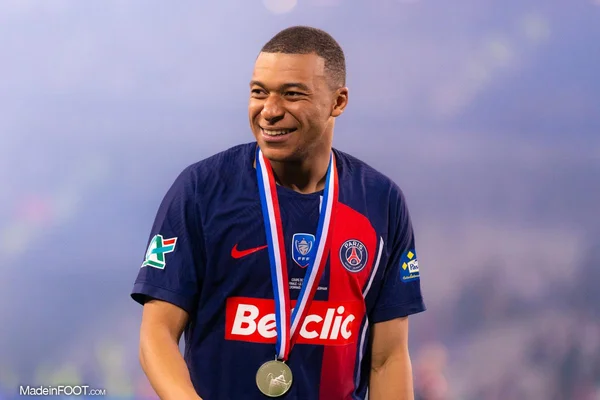 Kylian Mbappé fêtant un titre du PSG, médaille au cou, en maillot domicile.