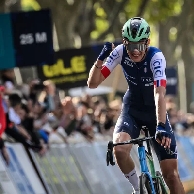 Paul Seixas célébrant sa victoire le poing levé devant les spectateurs lors d'une course cycliste.
