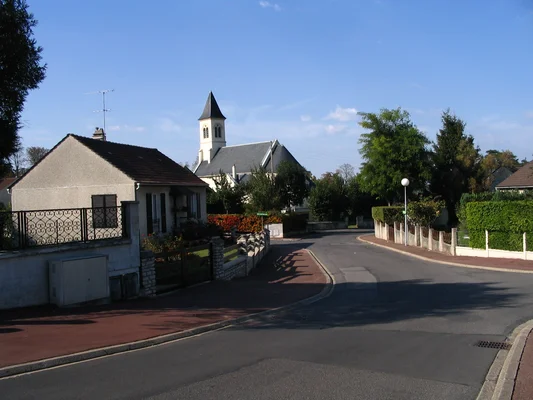 Une rue paisible de Noisiel dominée par une église et bordée d'arbres.