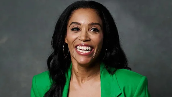 Sarah Bond, présidente d'Xbox, souriant en blazer vert sur fond neutre.