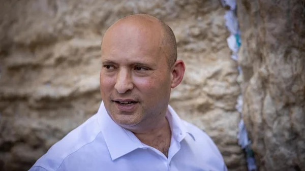 Naftali Bennett, ancien chef du gouvernement israélien, devant un mur en pierre.