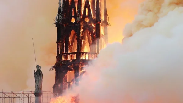 L'effondrement de la flèche de Notre-Dame dans un brasier intense, une statue au premier plan.