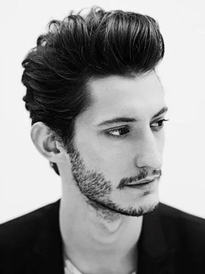 Portrait en noir et blanc de l'acteur Pierre Niney en blazer sombre.