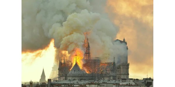 L'incendie de Notre-Dame de Paris, avec les flammes dévorant la structure sous un ciel crépusculaire.