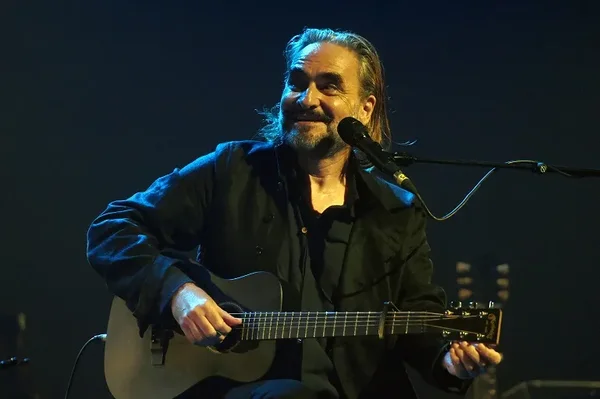 Vincent Delerm jouant de la guitare acoustique sur scène devant un microphone.