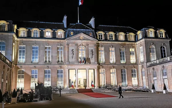 Le palais de l'Élysée la nuit, façade illuminée avec tapis rouge.