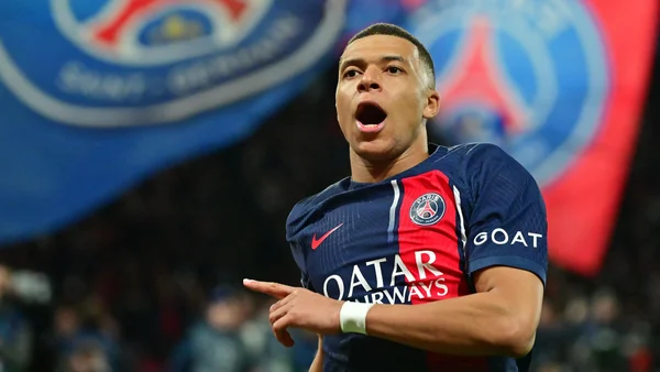 Kylian Mbappé en action lors d'un match du PSG, pointant du doigt devant les supporters.