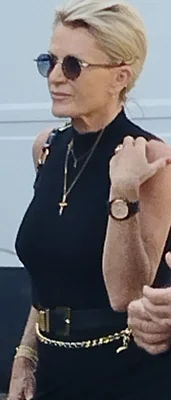 Sophie Davant en haut noir sans manches, collier croix et chaîne dorée, lunettes de soleil.