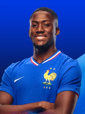 Ibrahima Konaté en maillot de l'équipe de France, bras croisés, posant devant un fond bleu