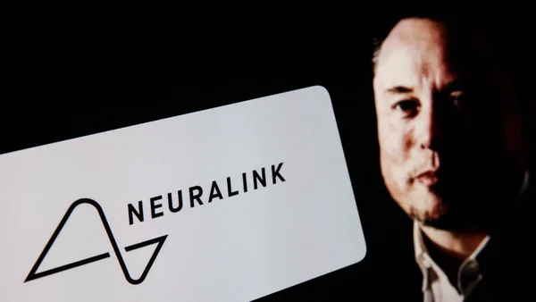 Une personne tenant une carte avec le logo Neuralink.