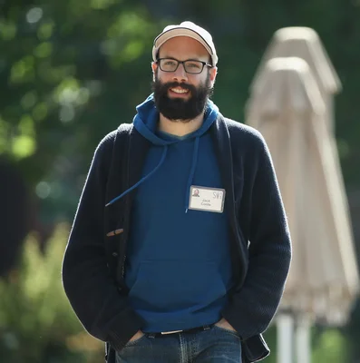 Jack Conte en extérieur portant un sweat bleu, un gilet et un badge nominatif.