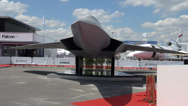 Modèle d'avion furtif exposé lors d'un salon aéronautique, avec des barrières aux couleurs de Dassault et Airbus.