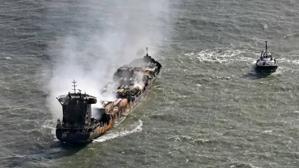 Un cargo en flammes après une collision spectaculaire en mer du Nord, assisté par un remorqueur.