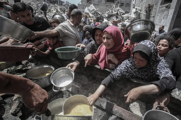 Un groupe de personnes autour de marmites de cuisine dans un paysage de ruines.