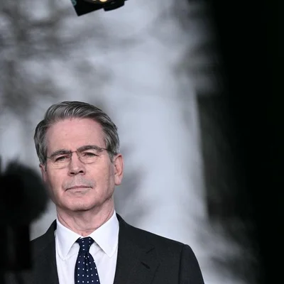 Homme en costume et lunettes lors d'une rencontre officielle.