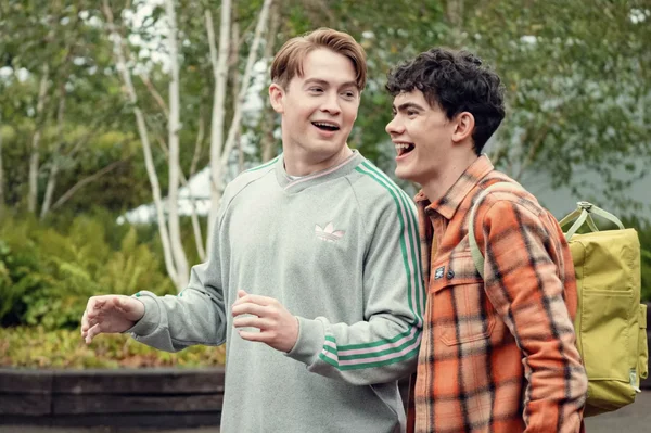 Kit Connor et Joe Locke souriants lors d'une scène en extérieur pour Heartstopper Forever.