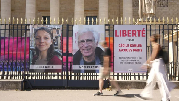 Portraits de Cécile Kohler et Jacques Paris sur une clôture face à l'Assemblée nationale à Paris.