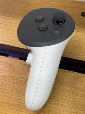 Une manette du Meta Quest 3 posée sur une surface en bois, montrant les boutons de contrôle.