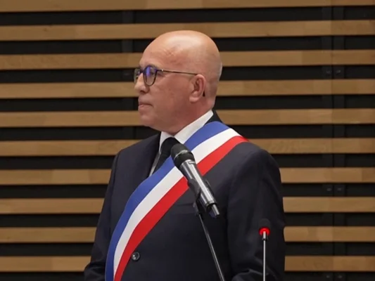 Éric Ciotti, revêtu de l'écharpe de maire, s'exprimant devant les médias.