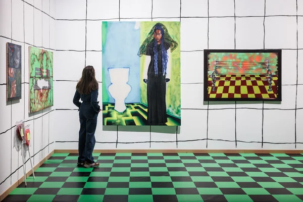 Une visiteuse découvrant une peinture colorée lors de l'exposition 100% L'EXPO à la Grande Halle de la Villette.