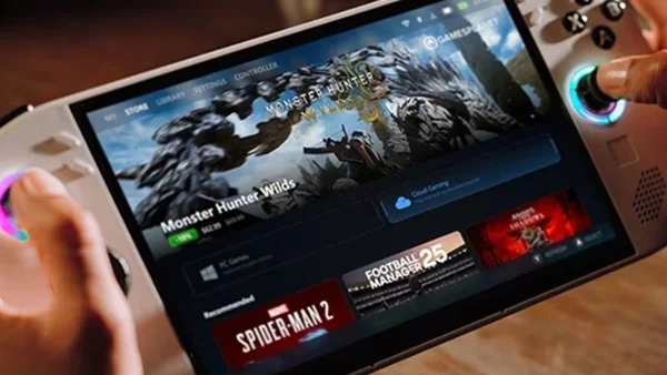 Des mains manipulent la console portable sur l'interface Steam avec Monster Hunter Wilds.