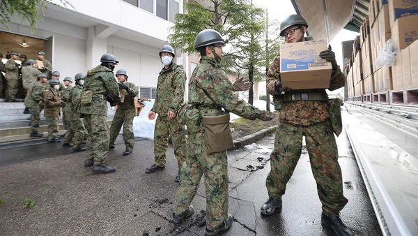 Des militaires des Forces japonaises d'autodéfense déchargeant du matériel d'un camion.