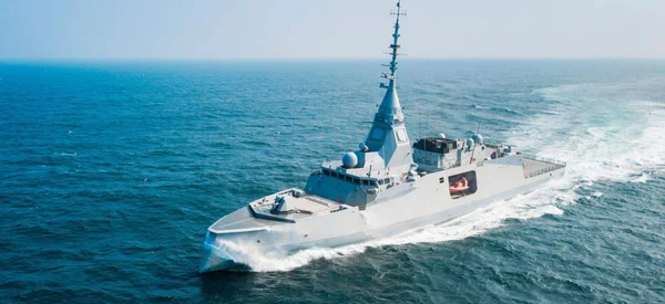 La frégate FDI en pleine mer, avec ses équipements radar et son sillage blanc caractéristique.