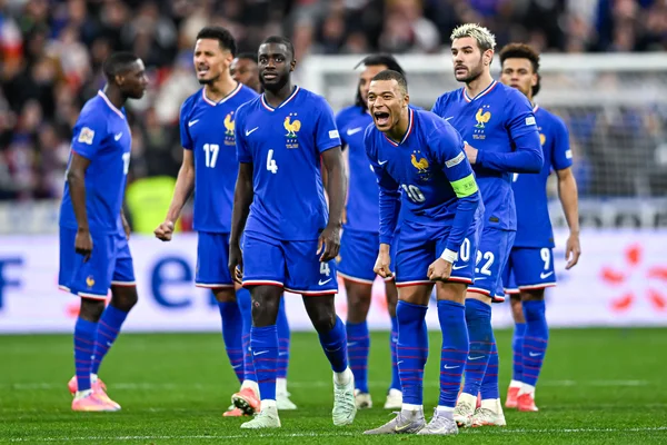 Le capitaine de l'équipe de France en maillot 10 célébrant au milieu de ses coéquipiers sur le terrain.
