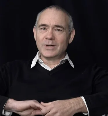 Christophe Boltanski en portrait officiel, assis et mains jointes.