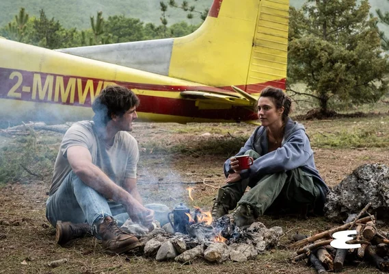 Jacob Elordi et Margaret Qualley partageant un moment près d'un feu de camp dans 'The Dog Stars'.
