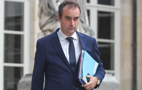 Sébastien Lecornu tenant des dossiers, debout à l'extérieur de l'Assemblée nationale.