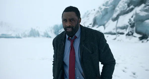 Idris Elba incarne l'inspecteur Luther dans une scène devant un bâtiment urbain.