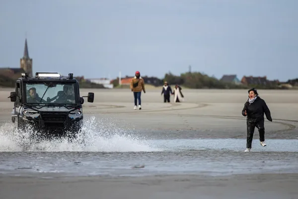 Un véhicule de police sur une plage de Gravelines près d'un migrant courant.