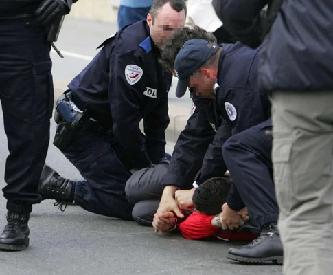 Un policier sur la plage observant un radeau de migrants sur l'eau.