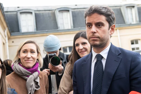 Des échanges politiques entre un homme en costume et d'autres personnes devant un bâtiment.