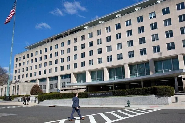 Le bâtiment Harry S. Truman, siège du département d'État américain, flanqué d'un drapeau des États-Unis.